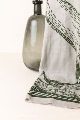 a green vase sitting next to a white towel