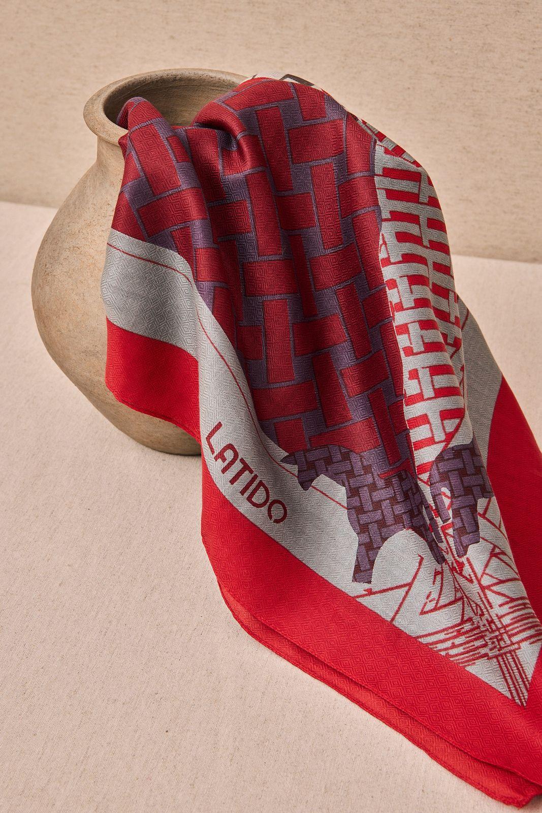 a red and grey scarf sitting on top of a vase