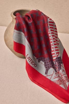 a red and grey scarf sitting on top of a vase