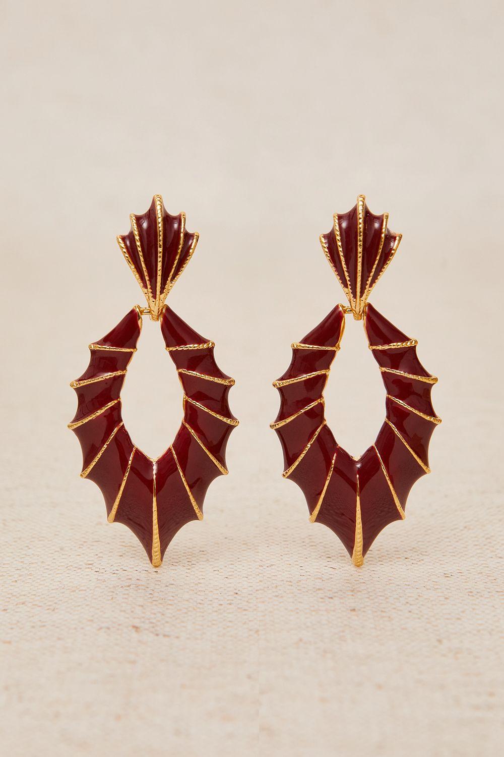 a pair of red and gold earrings on a white surface