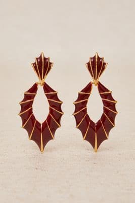 a pair of red and gold earrings on a white surface