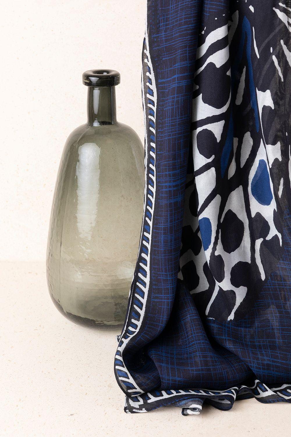 a vase sitting next to a scarf on a table