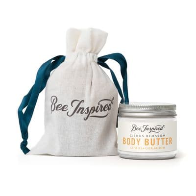 a jar of body butter next to a bag