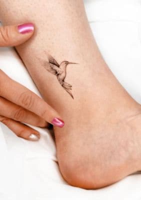 a woman's foot with a bird tattoo on it