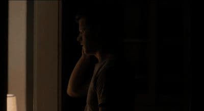 a man standing in a dark room next to a lamp