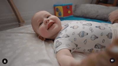 a baby laying on a bed with a toy