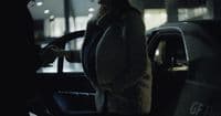 a woman standing next to a car talking on a cell phone