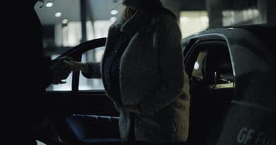 a woman standing next to a car talking on a cell phone