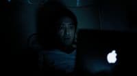 a man sitting in the dark with a laptop