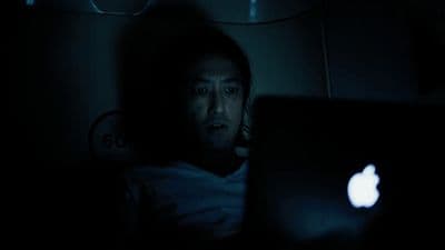 a man sitting in the dark with a laptop