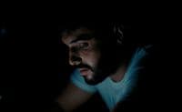 a man looking at a laptop in the dark