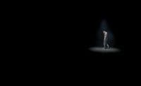 a man standing in the dark with his hands on his hips