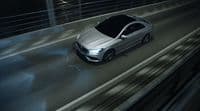 a silver car driving down a highway at night