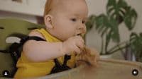 a baby sitting in a high chair eating food