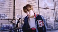 a boy in a blue jacket standing in front of a wall