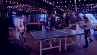 a group of people standing around a ping pong table