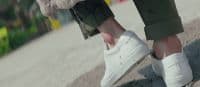 a person wearing white shoes and a furry coat