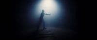 a man standing in the dark with his arms outstretched