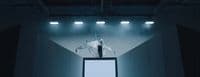 a man standing on top of a tv screen in a dark room