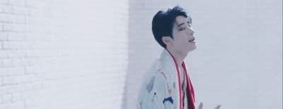 a man in a kimono standing in front of a brick wall