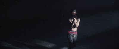 a shirtless man standing in a dark room