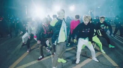 a group of young men dancing in a parking lot