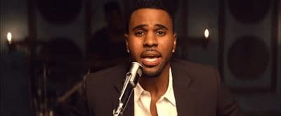 a man in a suit is singing into a microphone