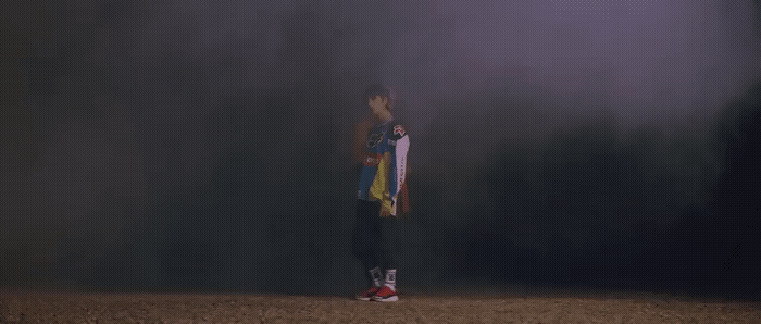 a man holding a skateboard standing in a field