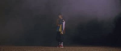 a man holding a skateboard standing in a field