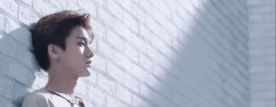 a man standing next to a brick wall