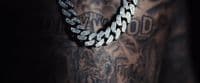 a man with a tattoo on his arm wearing a chain