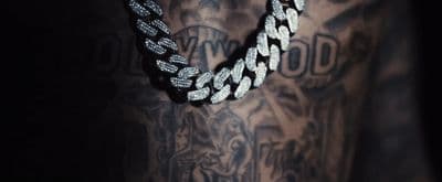 a man with a tattoo on his arm wearing a chain