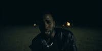 a man in a leather jacket sitting in the dark