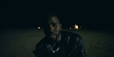 a man in a leather jacket sitting in the dark
