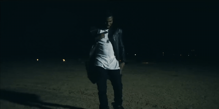 a man in a white shirt and black pants standing in the dark