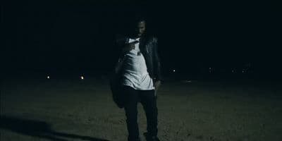 a man in a white shirt and black pants standing in the dark