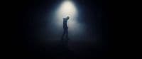 a person standing in the dark with their arms up in the air