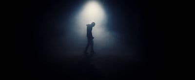 a person standing in the dark with their arms up in the air