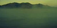 a foggy landscape with mountains in the distance