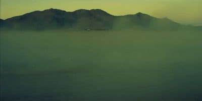 a foggy landscape with mountains in the distance