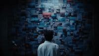 a man standing in front of a wall covered in pictures