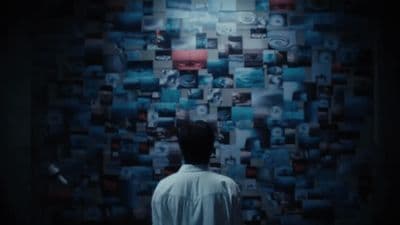 a man standing in front of a wall covered in pictures