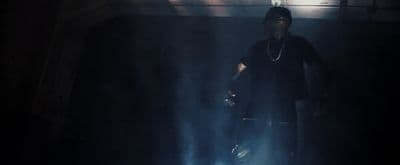 a man standing in a dark room with his hands in his pockets
