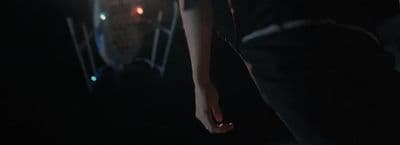 a person standing in the dark with their hand on their hip