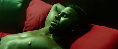 a shirtless man laying on a red pillow