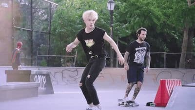 a man riding a skateboard next to another man on a skateboard