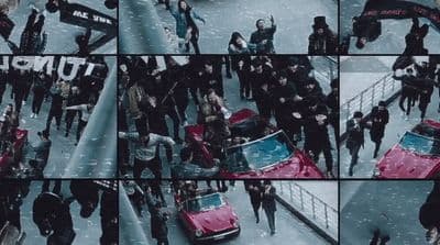 a group of people standing around a red car