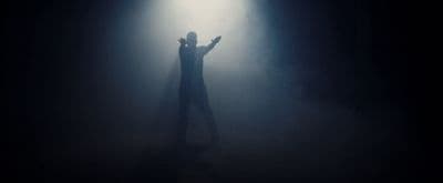 a person standing in the dark with their arms outstretched