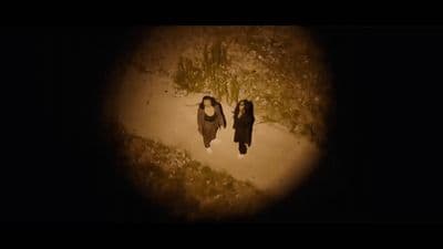 two women walking down a dirt road at night