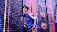 a young man standing in front of a colorful wall